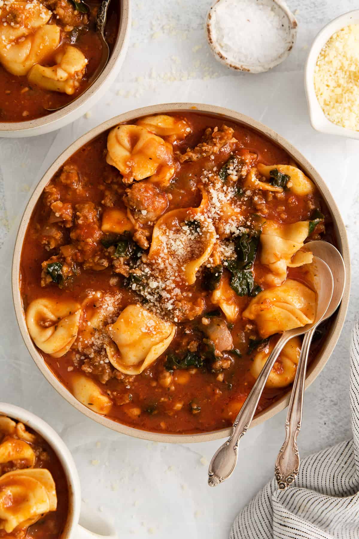 Cheese tortellini soup in a bowl with a spoon.