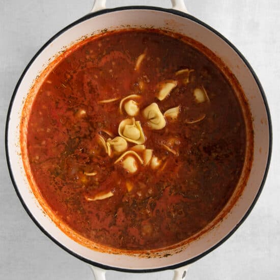 a pot of tomato soup with noodles in it.