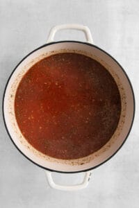 a pot of tomato sauce on a white surface.