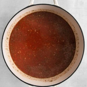 a pot of tomato sauce on a white surface.