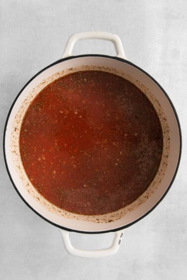 a pot of tomato sauce on a white surface.