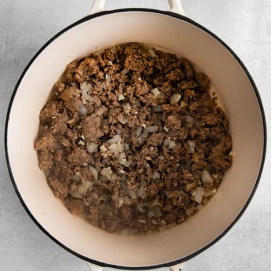 a pot filled with ground beef and onions.