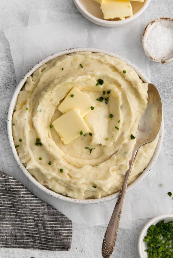 a bowl of mashed potatoes with butter and parsley.