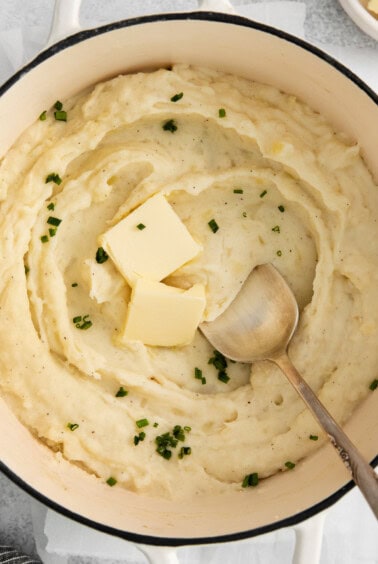 mashed potatoes in a pot with butter and parsley.
