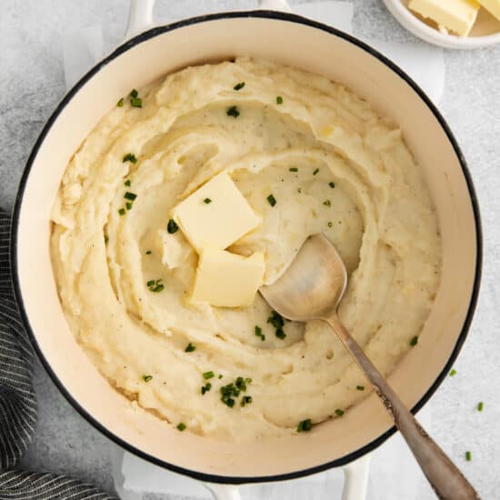 mashed potatoes in a pot with butter and parsley.