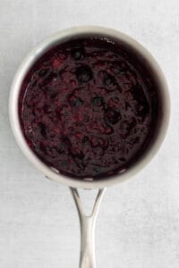 a spoonful of blueberry jam on a white surface.