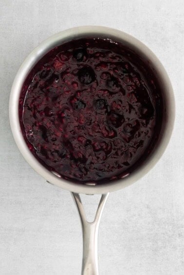 a spoonful of blueberry jam on a white surface.