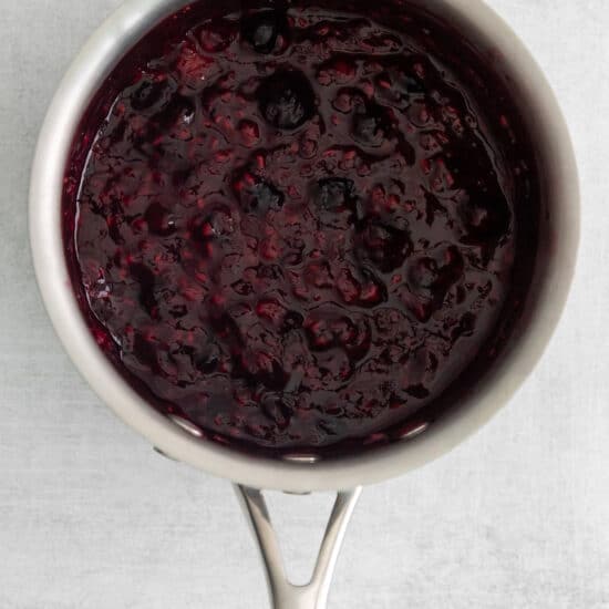 a spoonful of blueberry jam on a white surface.
