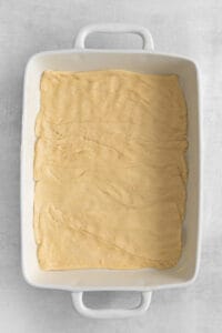 a square baking dish filled with dough.