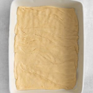 a square baking dish filled with dough.