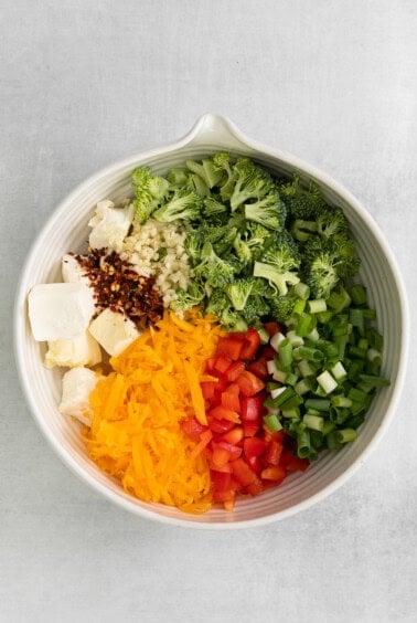 a white bowl filled with broccoli, cheese, and other ingredients.