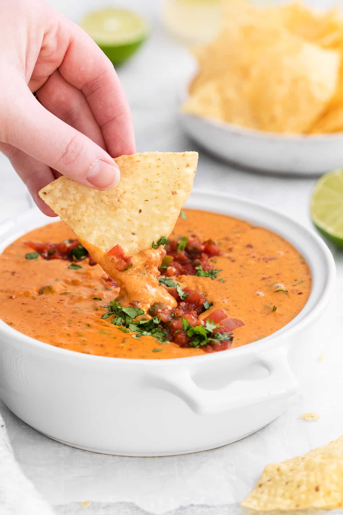 scooping Velveeta cheese dip with tortilla chips.