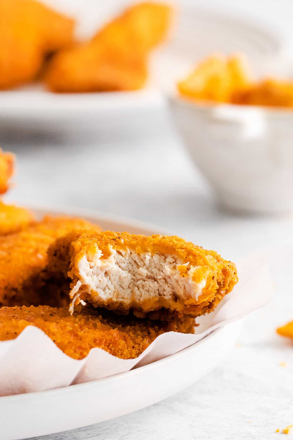 Cheez it breaded chicken finger with a bite taken out of it.