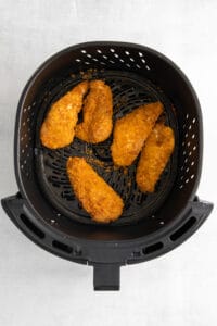 fried chicken in an air fryer on a white background.