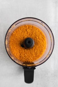 orange powder in a food processor on a white background.