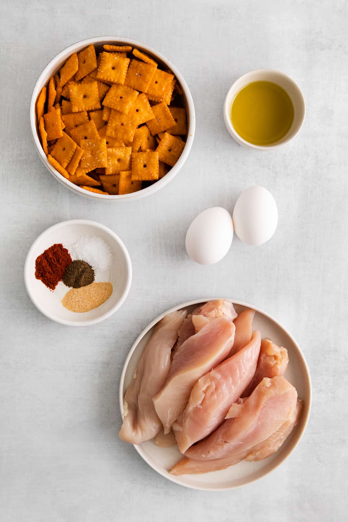 Ingredients for cheez-it breaded chicken fingers in bowls.