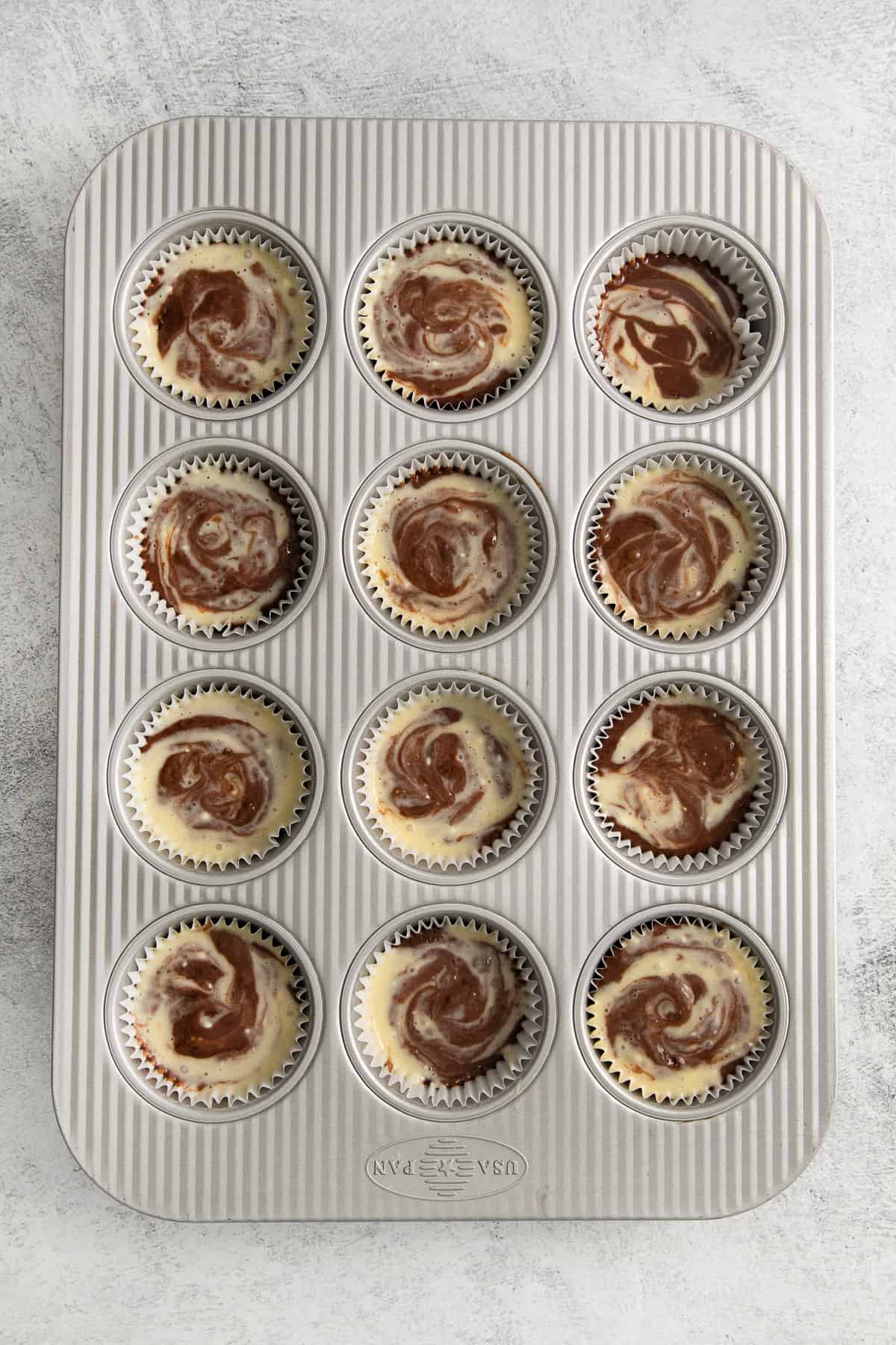 Cream cheese chocolate cupcakes in a muffin tin.