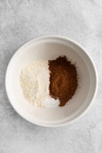 a white bowl with flour, cocoa powder, and sugar.