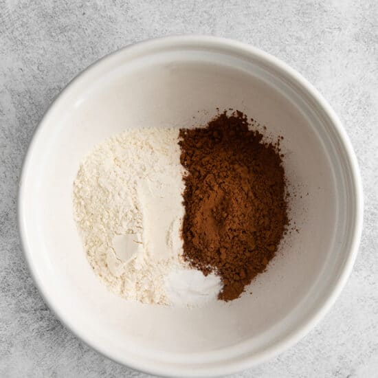 a white bowl with flour, cocoa powder, and sugar.