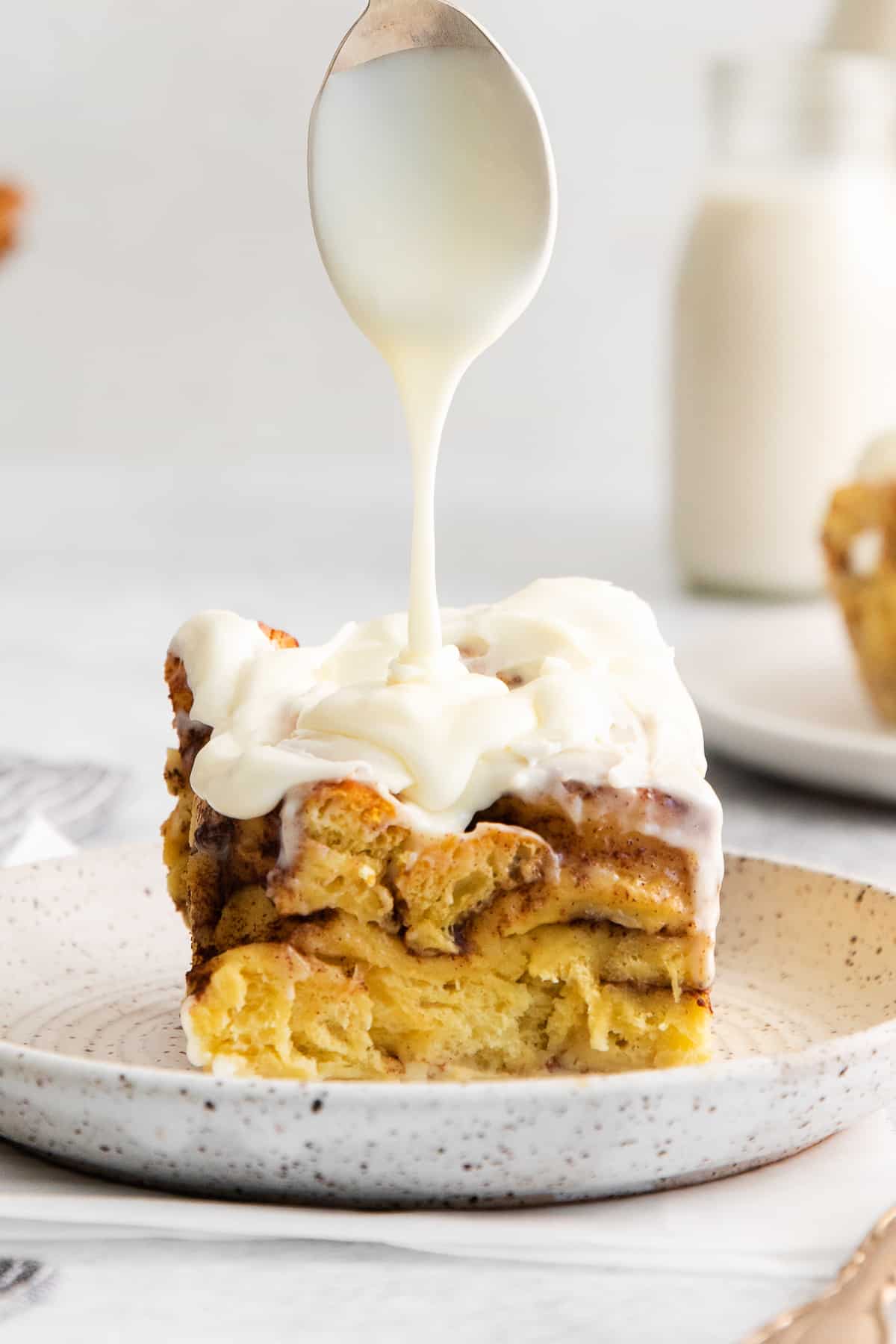 Slice of cinnamon roll casserole topped with icing.
