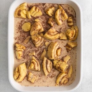 a white baking dish with cinnamon rolls in it.