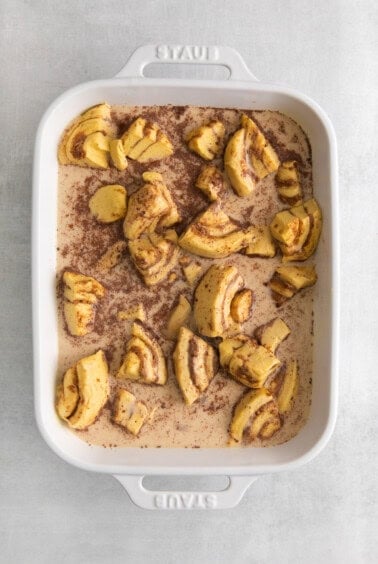 a white baking dish with cinnamon rolls in it.