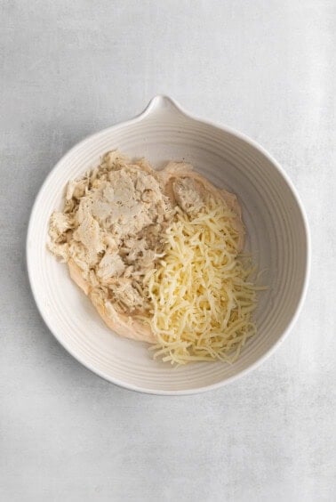 a white bowl with cheese and chicken in it.