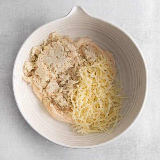 a white bowl with cheese and chicken in it.