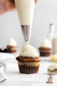 a person icing a cupcake with frosting.