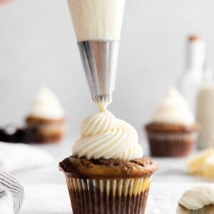 a person icing a cupcake with frosting.