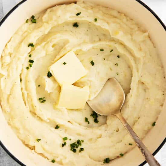Mashed potatoes in a pot with butter and parsley.
