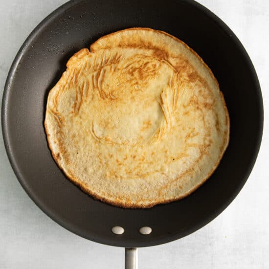 a pancake in a frying pan on a white background.
