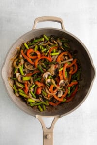 a frying pan filled with vegetables and mushrooms.
