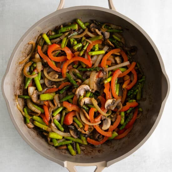 a frying pan filled with vegetables and mushrooms.