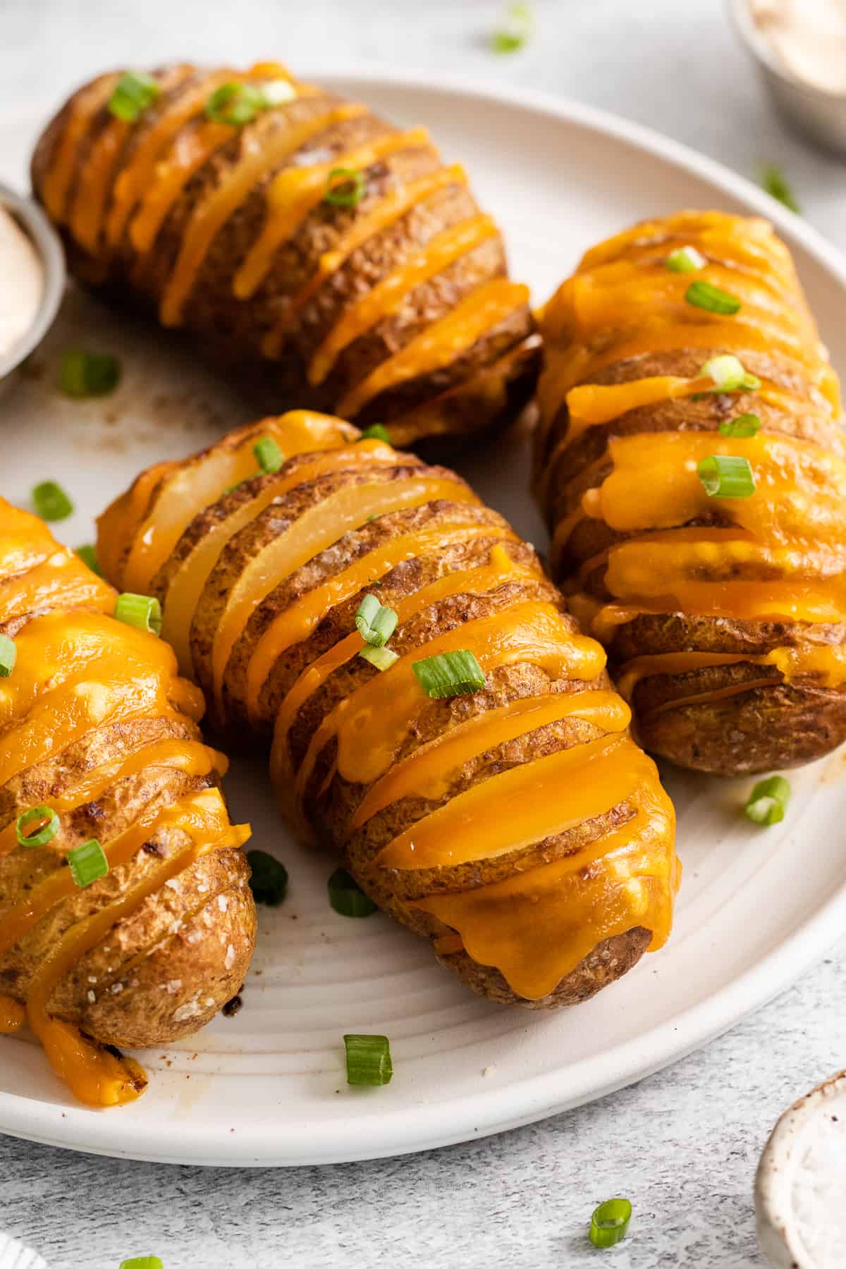 Hasselback potatoes on a plate topped with chives.