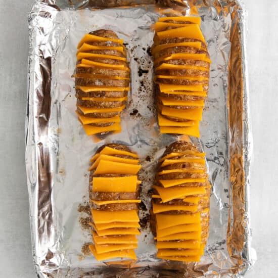 sliced sweet potatoes in foil on a baking sheet.