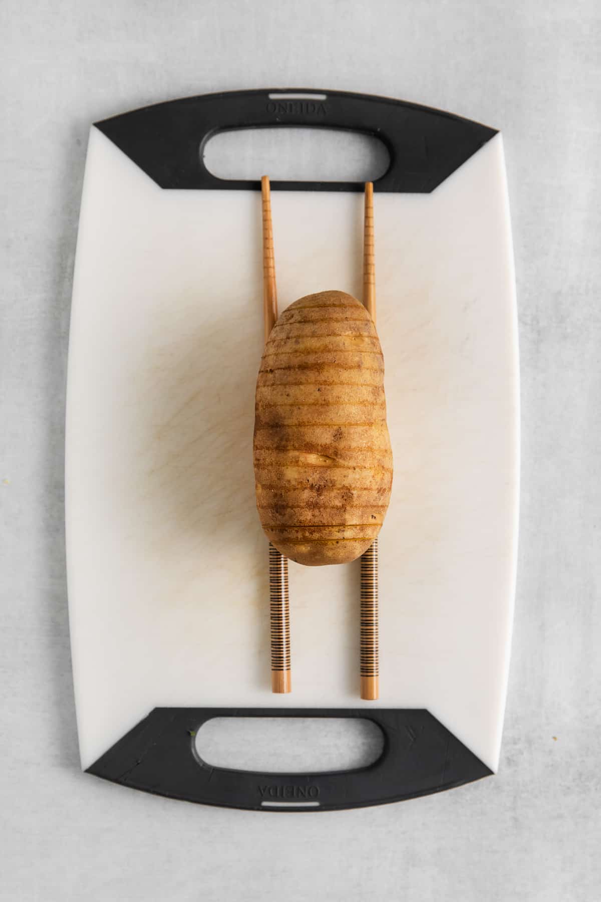 Potato sliced hasselback style on a cutting board.