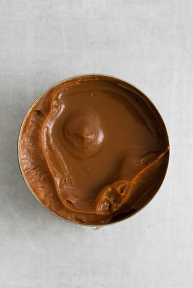 peanut butter in a tin on a white surface.