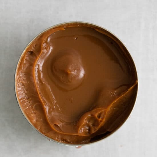 peanut butter in a tin on a white surface.