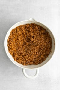 a white dish filled with a mixture of brown sugar and cinnamon.