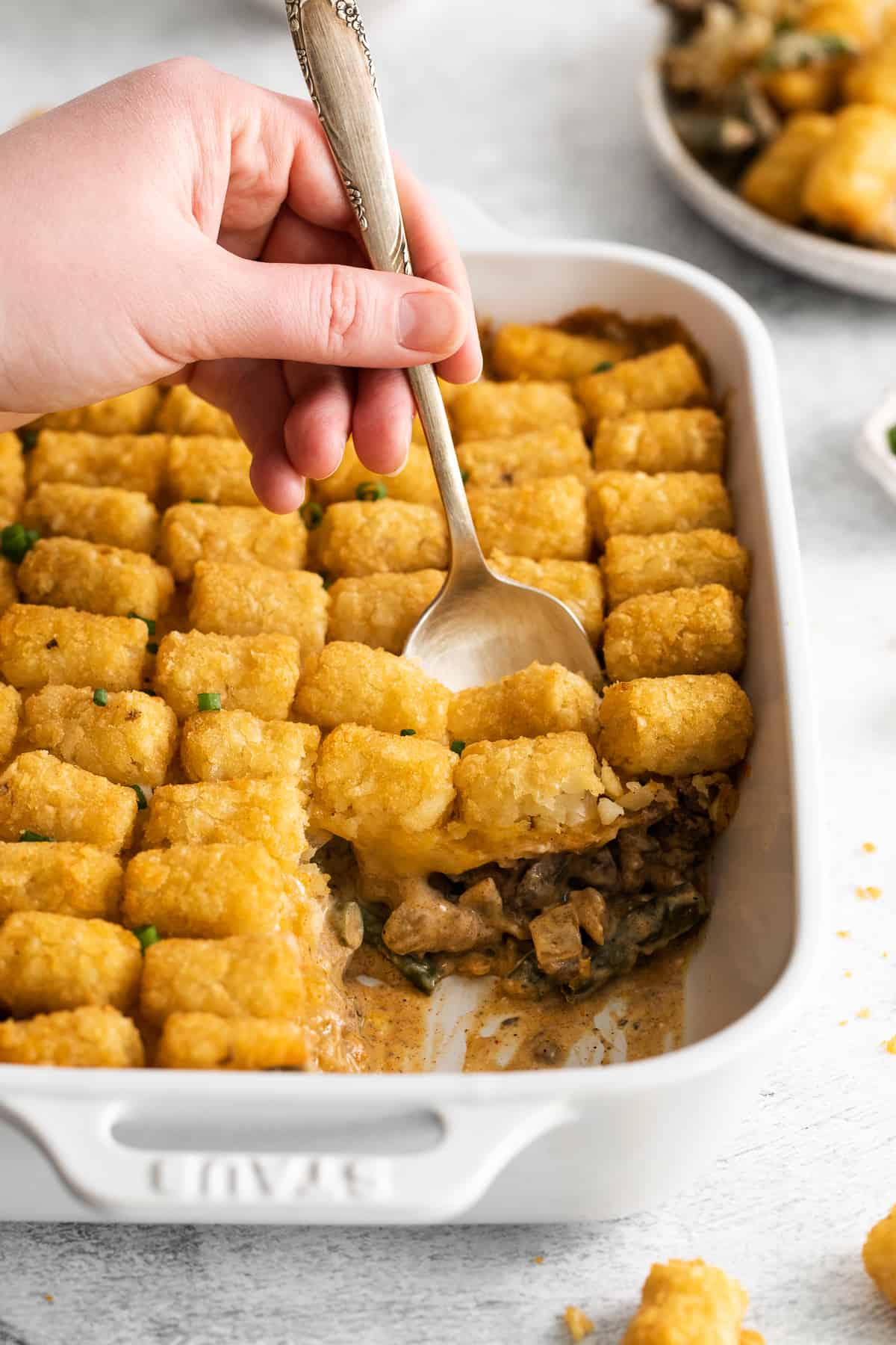 A spoon scooping tater tot hot dish.