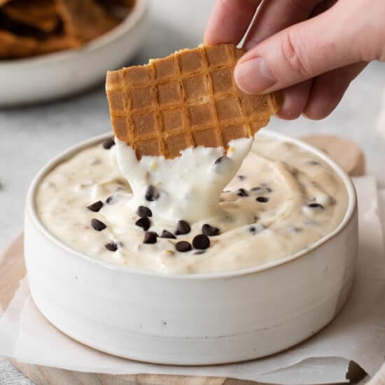 Waffle cone being dipped into cannoli dip.