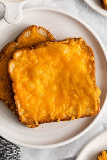 a plate of cheesy toast on a white plate.
