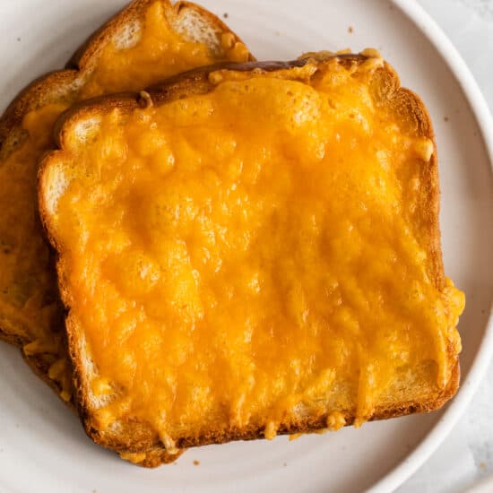 a plate of cheesy toast on a white plate.
