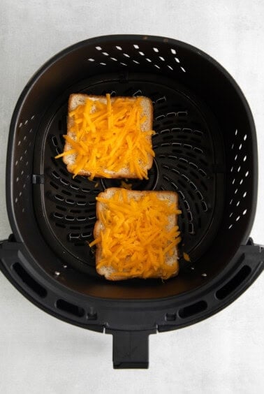 two slices of bread and cheese in an air fryer.