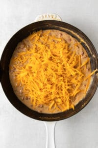 a skillet filled with cheesy beans and cheese.