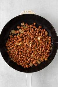 a skillet filled with beans and onions.