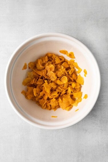 a bowl of corn flakes on a white surface.