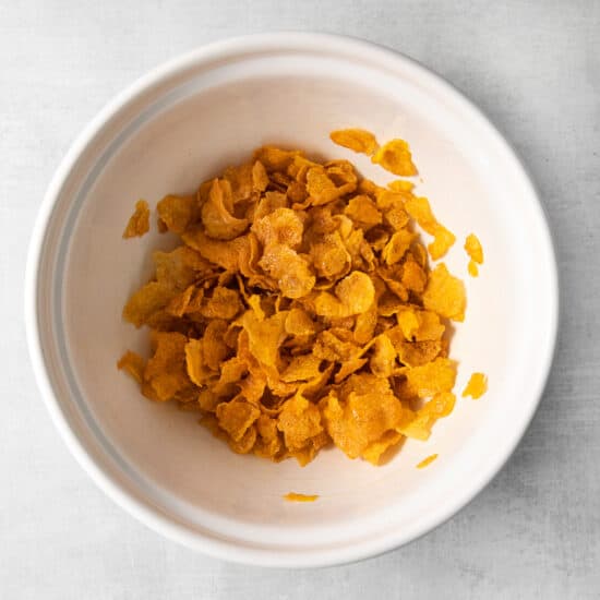 a bowl of corn flakes on a white surface.
