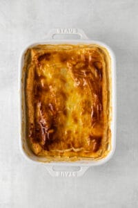 a white casserole dish with a cheesy dish in it.